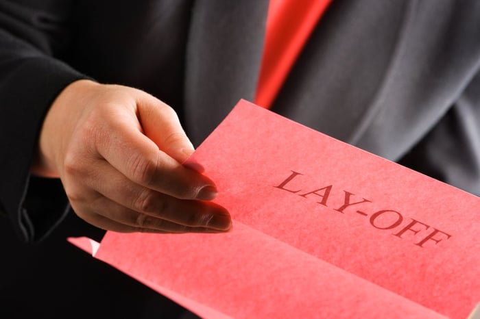 Person in a suit, holding a layoff notification.