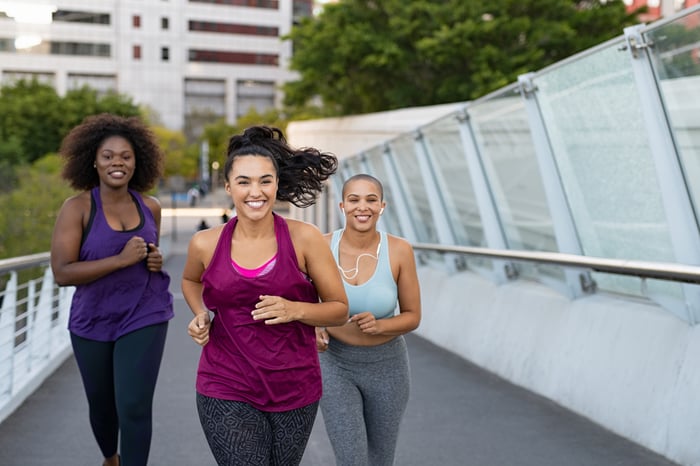 A group of friends running or jogging, wearing workout attire.