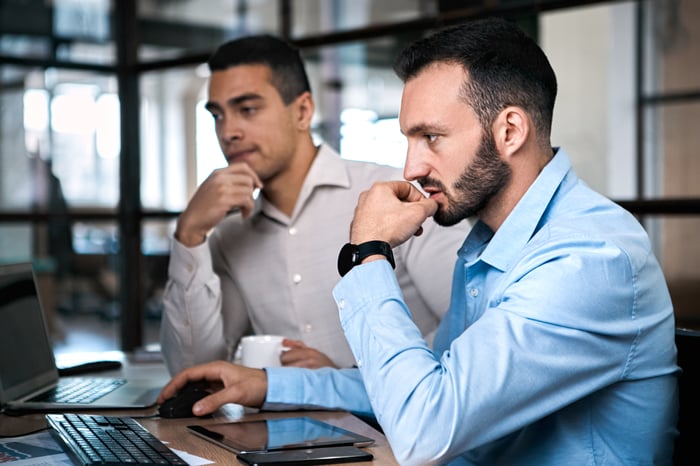 Two pensive investors work side-by-side.