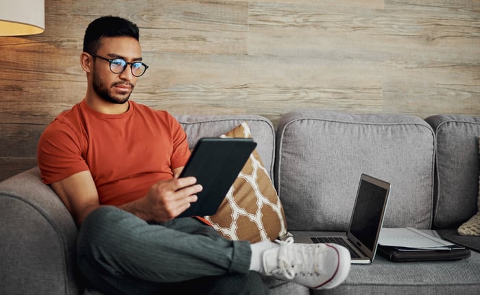 A person on a couch holding a tablet.