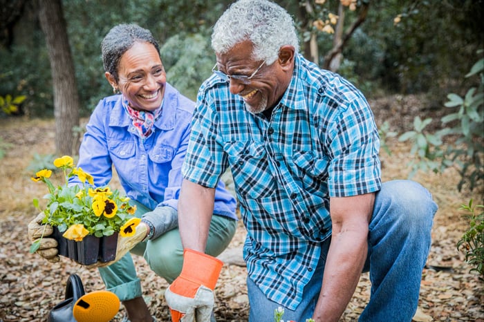 An older couple enjoyng time planting flowers in a garden.
