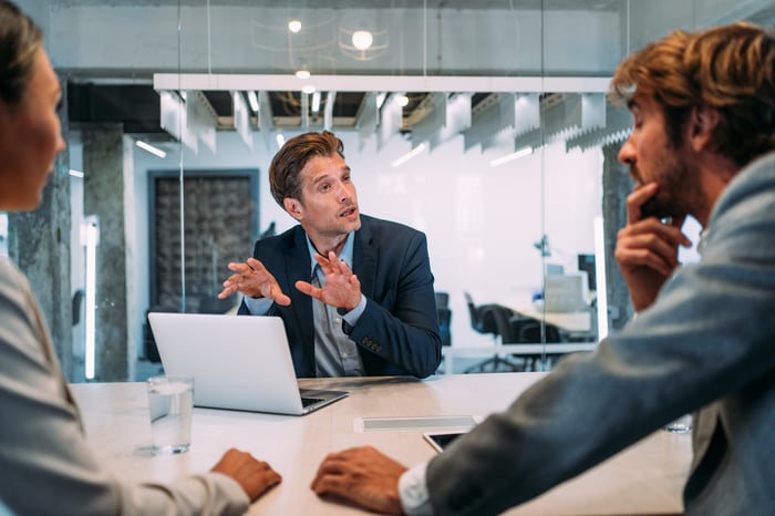 Workers in a meeting room have a discussion.
