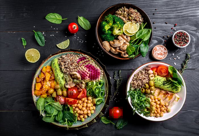 3 bowls sit on a table. The bowls have food in them.