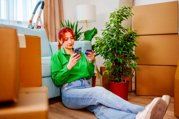 Person looking at a phone in one hand and a credit card in the other. 