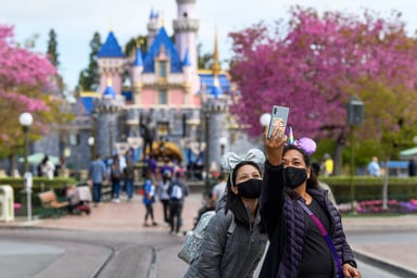 Tourists at Disneyland taking a photo in front of Sleeping Beauty Castle