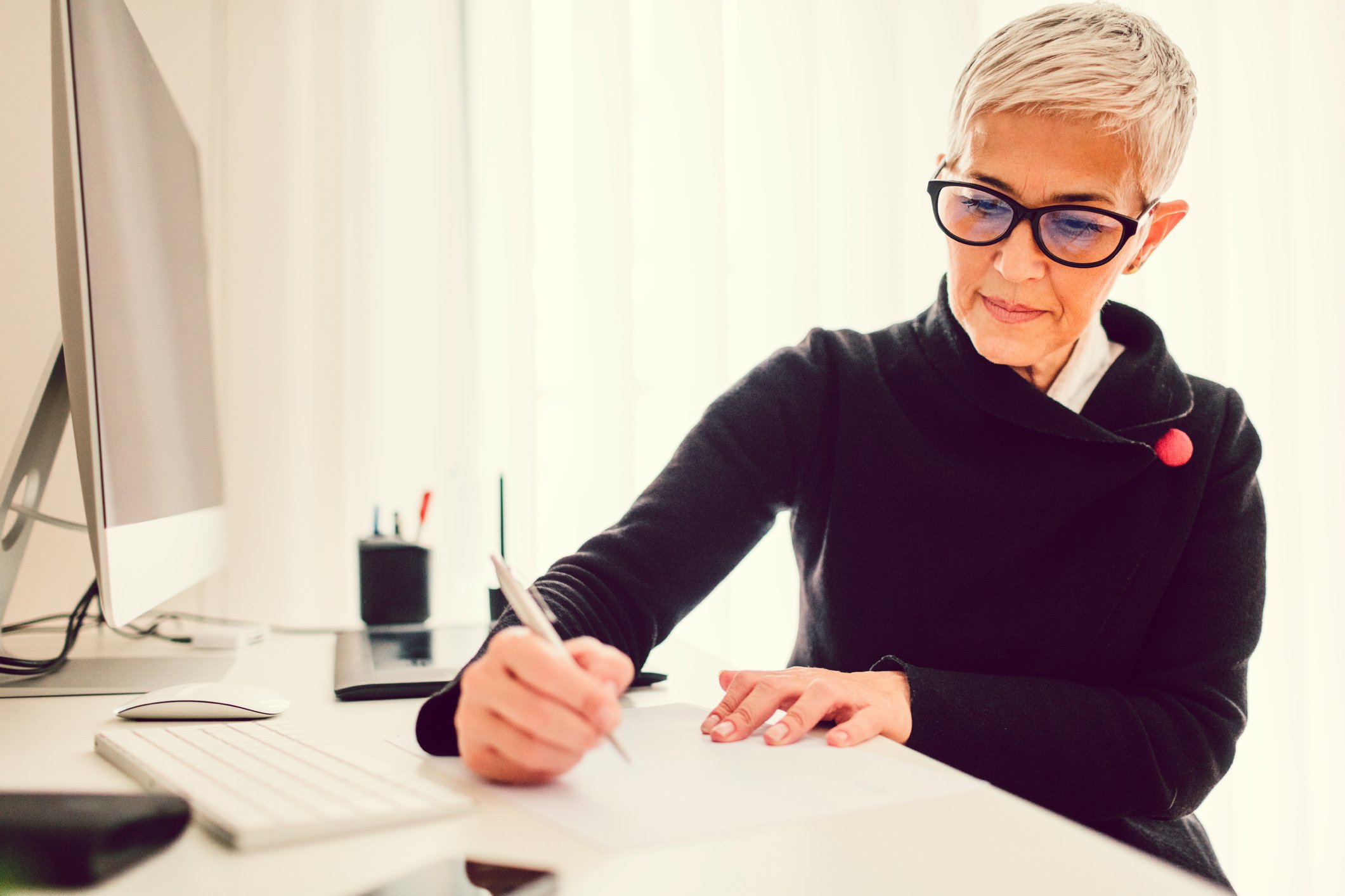 A person at a desk holding a pen_GettyImages-623450262