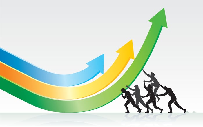 Several people in silhouette pushing charting arrows upward.