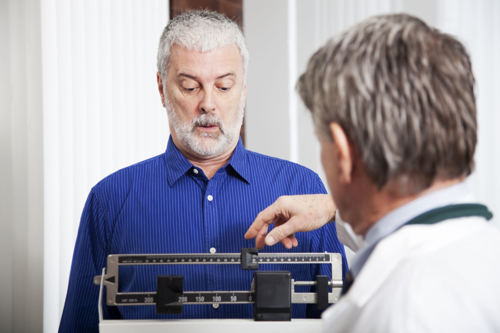 A physician using a scale to measure a person's weight.