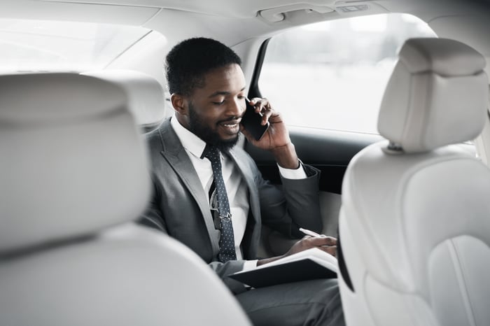 A passenger talking on the phone in the backseat of a car.