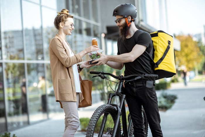 A man on bike delivering food to a lady.