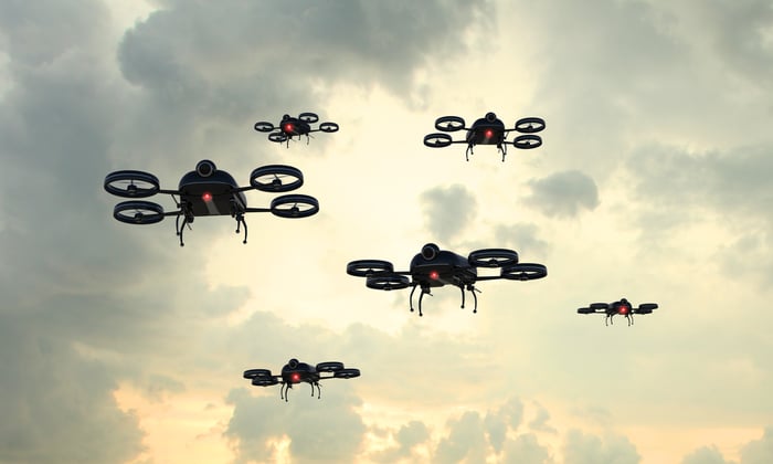 Several drones flying against a cloudy backdrop. 