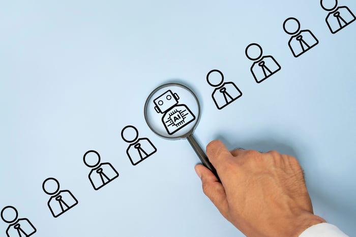 A drawing of an AI bot in a lineup of humans. A person holds a magnifying glass over the bot. 