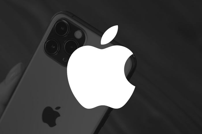 The Apple logo in front of a hand holding an iPhone on a black background.