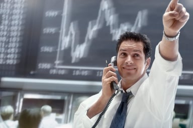 A person on the phone pointing to movement on a stock chart