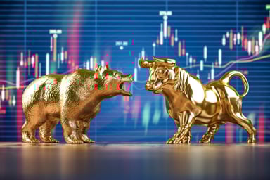 A gold bull and bear facing off in front of a large stock market chart