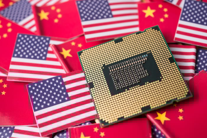 A microchip sits on a pile of miniature US and Chinese flags.