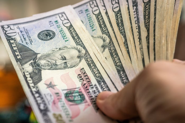 A hand holding $50 bills.