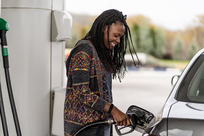 A woman fuels up her car at a gas pump.