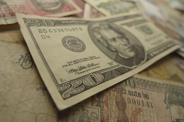 A picture of a twenty-dollar bill on top of other money. 