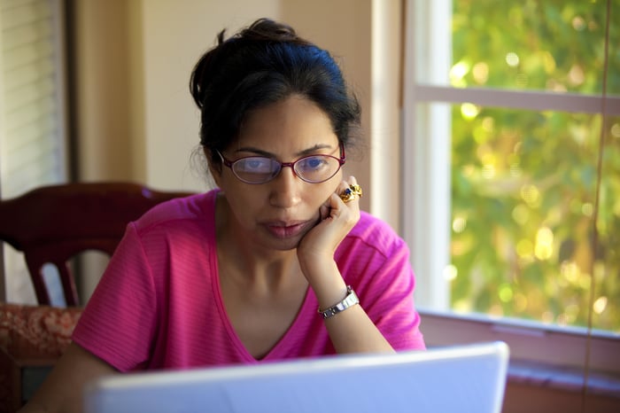 Serious-looking person staring intently at a laptop.