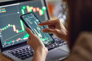 looking at stock charts on laptop and smartphone
