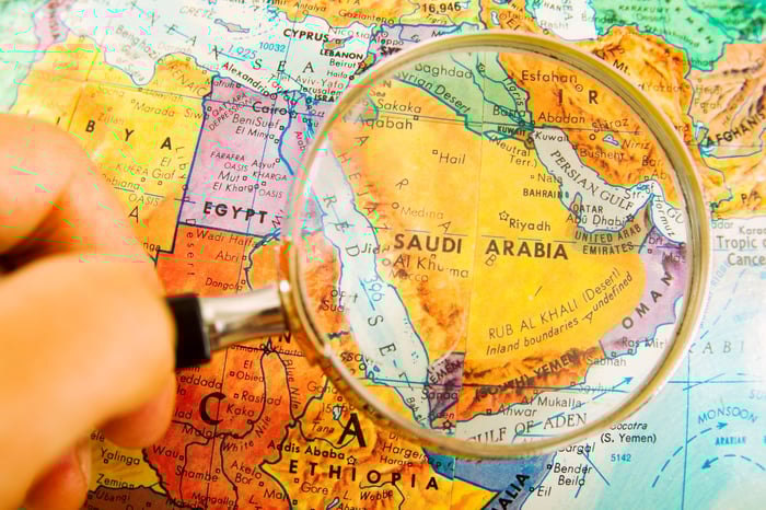 A person using a magnifying glass on a map of the Middle East.