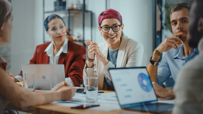 Professionals smiling and discussing in an office meeting.