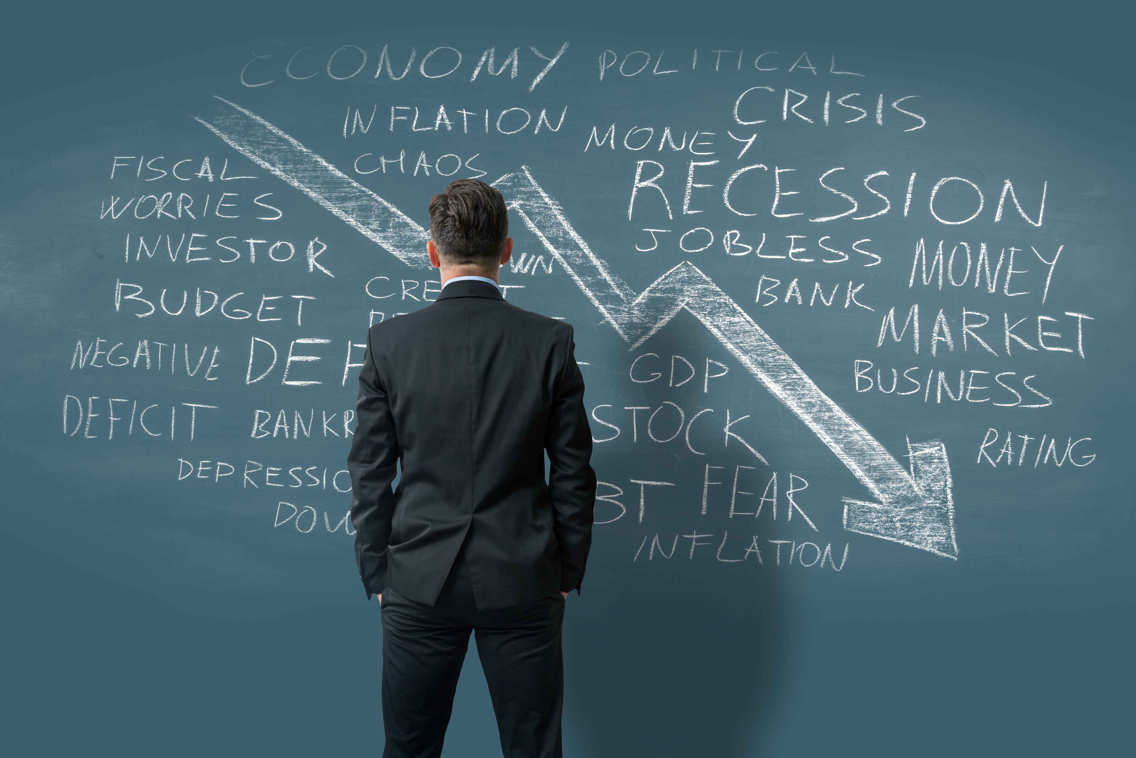 Businessman in front of chalkboard with inflation recession GDP