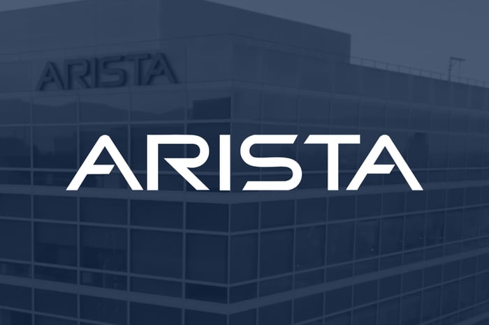 The Arista Networks logo superimposed over a picture of the company's headquarters building.