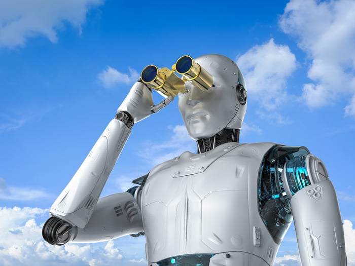 A humanoid robot looks through a pair of golden binoculars.