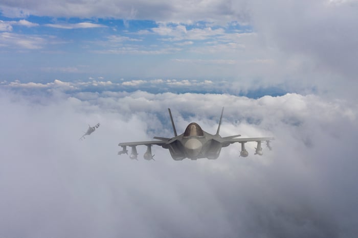 A fighter airplane flies in the clouds. 