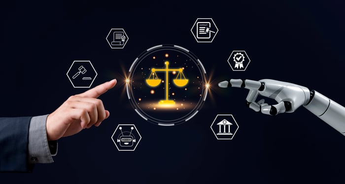 A human hand and robot hand point to each other. In the middle of both is a scale.