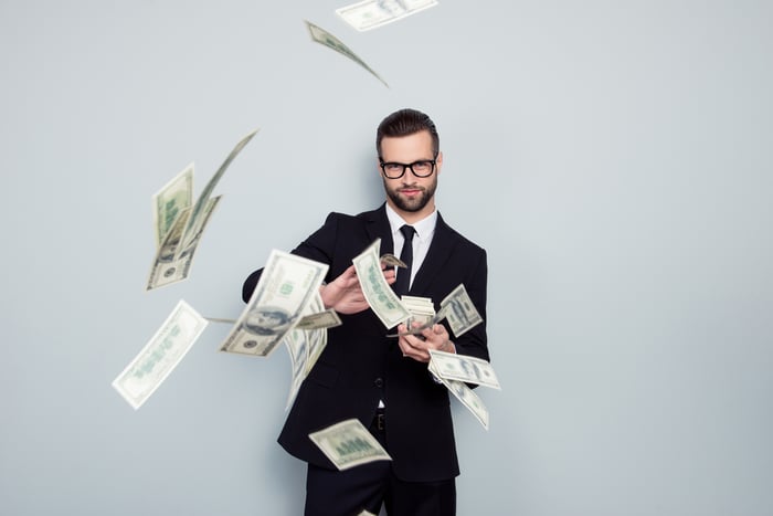 A person in a suit tossing money.