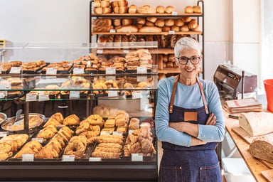 Senior woman working A smiling person wearing an apron in a bakery_GettyImages-1283480932