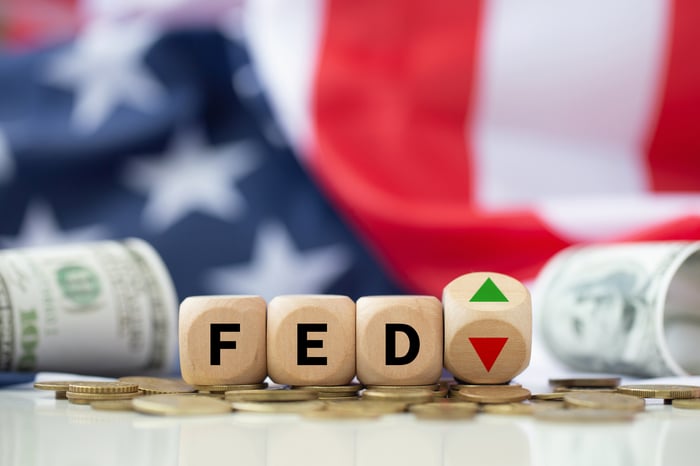Wooden blocks spelling FED next to up and down arrows with an American flag background.