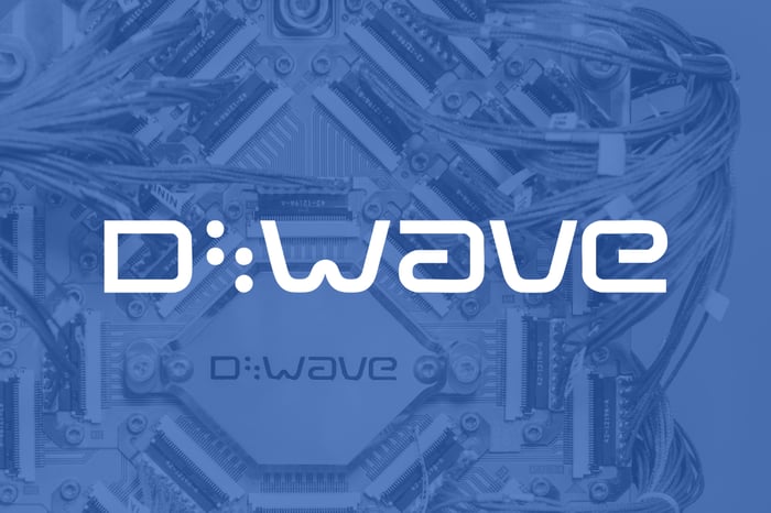 white D-Wave logo set over blue shadow picture of quantum computer internals.