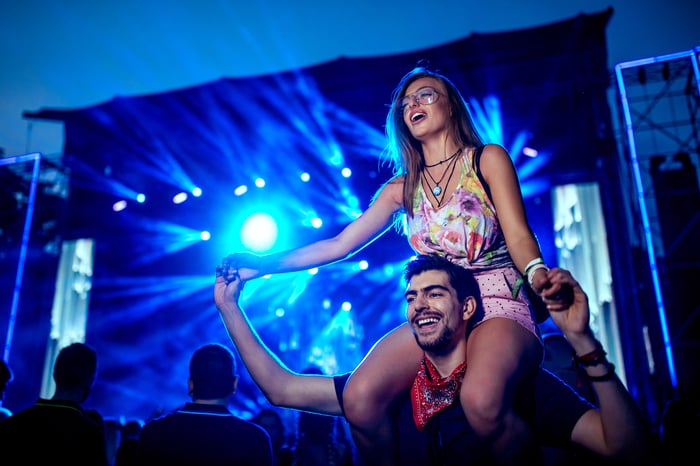 Woman on man's shoulders at concert. 