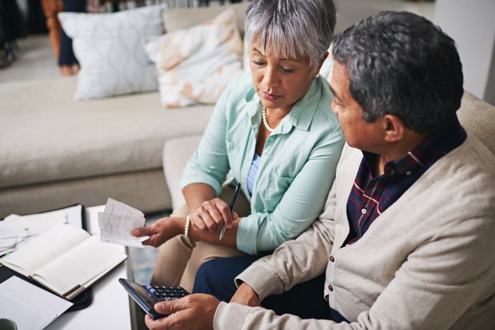 Two people holding calculators and receipts while having a discussion.