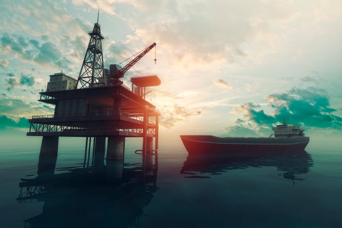 An oil tanker next to an oil rig.