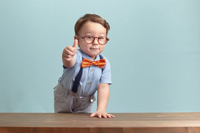young boy dressed in bowtie gives thumbs up.
