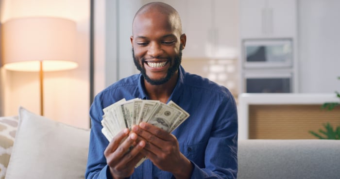 A smiling person holding cash.