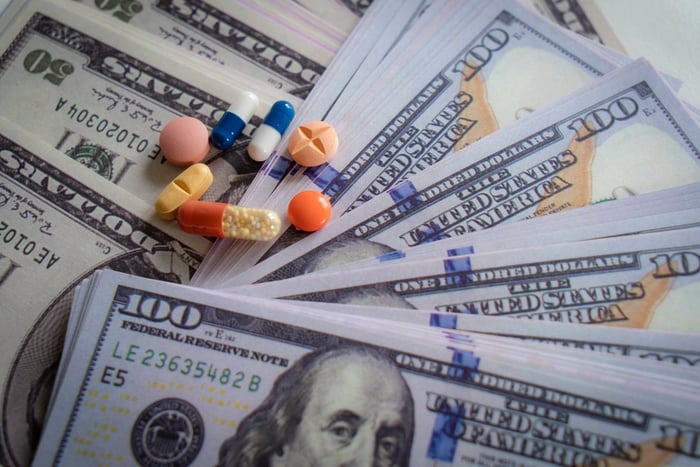 Pills and capsules on top of scattered American bills. 