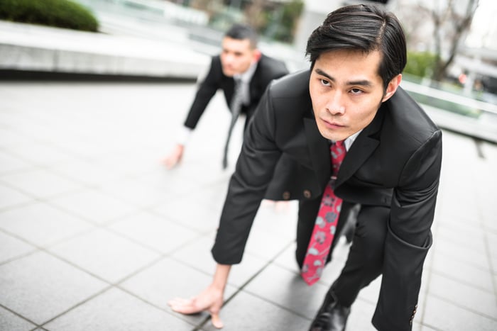 Two people in suits crouched down to begin a race. 