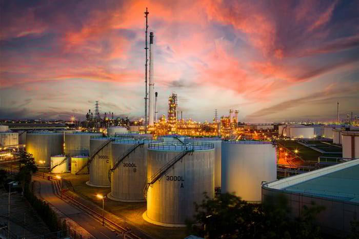 Oil storage tanks with a sunset in the background.