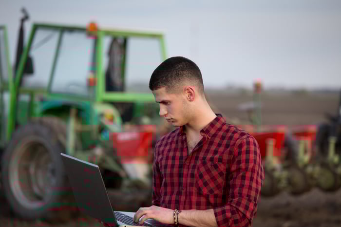A farmer checks information on a laptop.