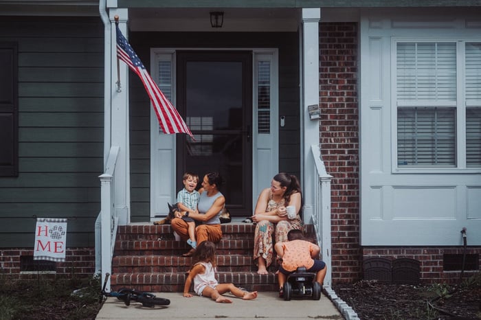 Two mothers on a stoop with three children.