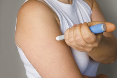 Woman injecting self in arm with a GLP-1 injector pen.
