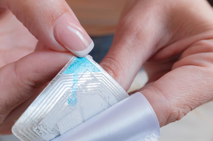 Two hands ataching an RFID tag to an object.