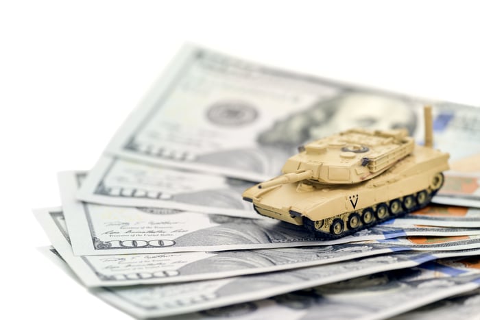 A toy tank sitting atop some dollars