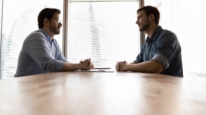Two people sitting across from one another at table.
